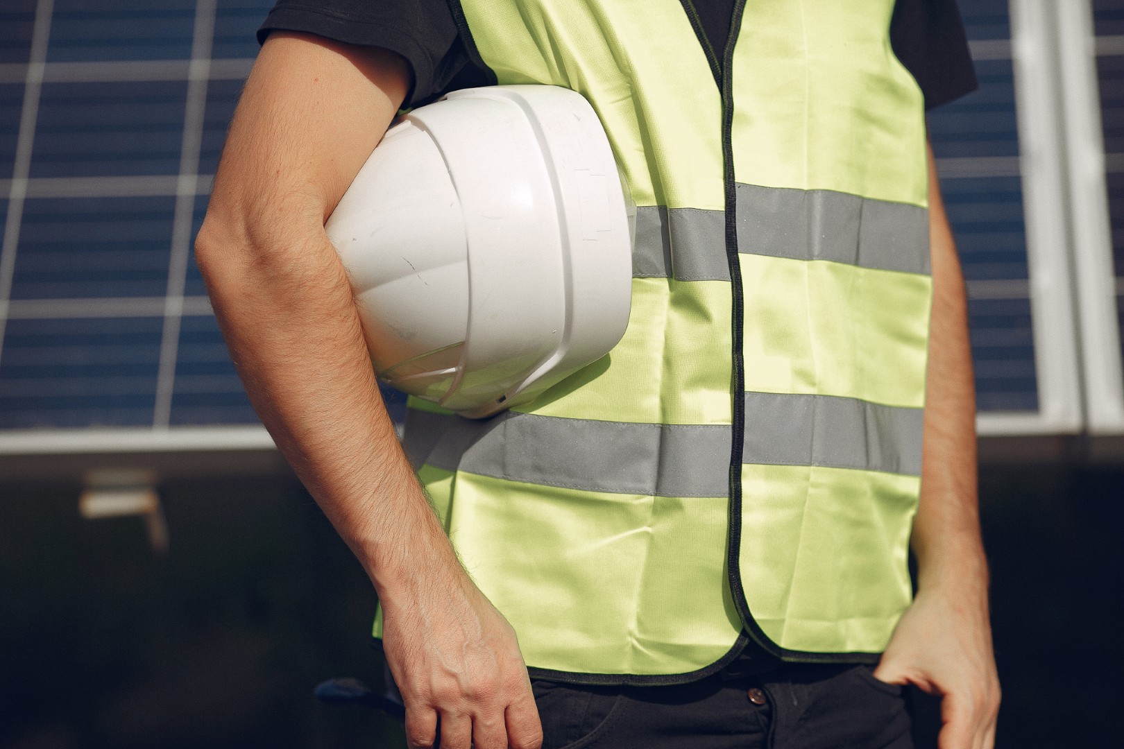 Addetto con gilet ad alta visibilità e casco in un impianto fotovoltaico